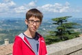 Young boy spectacled looking at camera outdoor over San Marino city-state. Vision, eyesight, sight, diopters, spectacles Royalty Free Stock Photo