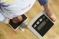 Young boy standing on digital scales cropped waist down