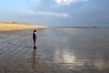 Young boy standing on an empty deserted beach at low tide, with