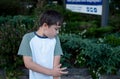 Young boy standing in the park scratching his arm,Child itchy skin from insect bite in the garden,Allergic kid scratching itchy Royalty Free Stock Photo