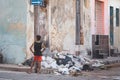 Young boy standing in an urban city street with a pile of discarded items at his side