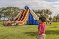 A young boy stands in the foreground, looking at the huge inflatable bounce house trampoline in the distance Royalty Free Stock Photo