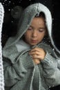 A young boy stands at the window with a raindrop on the glass after the rain