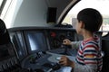 A young boy steering a locomotive and train in a driving compartment or cabin with handles and meters as a train driver Royalty Free Stock Photo