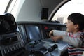 A young boy steering a locomotive and train in a driving compartment or cabin with handles and meters as a train driver Royalty Free Stock Photo