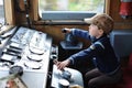 A young boy steering a locomotive and train in a driving compartment or cabin with handles and meters as a train driver Royalty Free Stock Photo