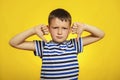 A young boy in striped t-shirt showing thumbs down gesture  with two hands on yellow background. Displeased child giving thumbs Royalty Free Stock Photo