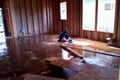 Boy studies for school in the only dry spot in the middle of a flooded room without furniture.