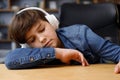 Young boy studying remotely at home using laptop. Tired schoolboy falling asleep during an online lesson with teacher Royalty Free Stock Photo