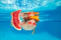 Young boy swim and dive underwater, hold watermelon. Under water portrait in swim pool. Child boy diving into a swimming Royalty Free Stock Photo