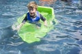 Young boy in swimming pool with green plastic boat