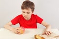 Young boy at the table chooses between hamburger and apple on white background Royalty Free Stock Photo