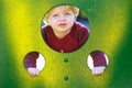 Young boy or toddler looking through holes in a wall in a playground Royalty Free Stock Photo