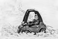 Young Boy in a Toy Car Stuck in the Snow - Black and White Royalty Free Stock Photo