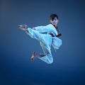 Young boy training karate on blue background Royalty Free Stock Photo