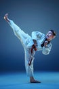 Young boy training karate on blue background Royalty Free Stock Photo