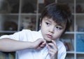 Young boy trying to close white polo shirt buttons, Emotional portrait of Kid sitting in bed looking out deep in through while