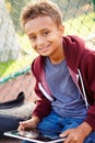 Young Boy Using Digital Tablet Sitting In Park Royalty Free Stock Photo