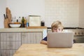 Young boy using laptop computer at kitchen table Royalty Free Stock Photo