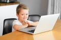 A young boy using a laptop computer sitting on top of a table at home Royalty Free Stock Photo