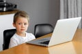 A young boy using a laptop computer sitting on top of a table at home Royalty Free Stock Photo