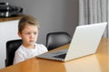 A young boy using a laptop computer sitting on top of a table at home Royalty Free Stock Photo