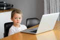 A young boy using a laptop computer sitting on top of a table at home Royalty Free Stock Photo