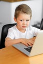 A young boy using a laptop computer sitting on top of a table at home Royalty Free Stock Photo