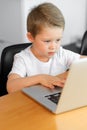 A young boy using a laptop computer sitting on top of a table at home Royalty Free Stock Photo