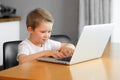 A young boy using a laptop computer sitting on top of a table at home Royalty Free Stock Photo