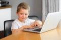 A young boy using a laptop computer sitting on top of a table at home Royalty Free Stock Photo