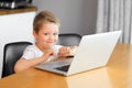 A young boy using a laptop computer sitting on top of a table at home Royalty Free Stock Photo