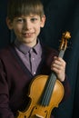 Young boy violinist sitting with his violin in the studio Royalty Free Stock Photo