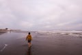 Young boy walking along the sandy shore on a cloudy day. Royalty Free Stock Photo