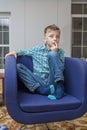 Young boy watch television sitting in blue chair in living room. Kid with blue eyes while watching TV. ÃÂ¡lose up view Royalty Free Stock Photo
