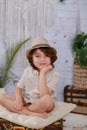 Young boy wearing a hat is sitting on a suitcase, looking off into the camera Royalty Free Stock Photo