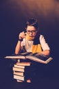 Young boy wearing a red-yellow scarf and glasses reading books on a black background. Concept of Imagination and Magic.