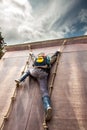 Young boy in wellys climbing up a wall with ropes