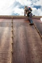 Young boy in wellys climbing up a wall with ropes