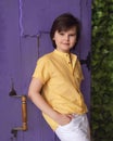 Young boy in a yellow shirt stands next to purple door. Studio shot. Concept of vacation and holidays Royalty Free Stock Photo