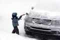 A little boy brushing snow from a car