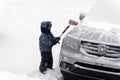 A little boy brushing snow from a car