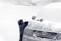 A little boy brushing snow from a car