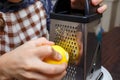 Young boy zesting lemon with grater at home kitchen