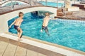 Young boys with bare torsos jumping into swimming pool