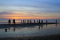 The young boys are playing football on the beach on the background of colorful sunset.
