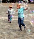 Young boys run after soap bubbles and catch them