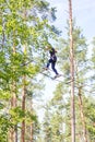 Young brave woman climbing in adventure rope park