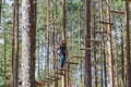 Young brave woman climbing in adventure rope park