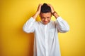 Young brazilian businessman wearing elegant shirt standing over isolated yellow background suffering from headache desperate and